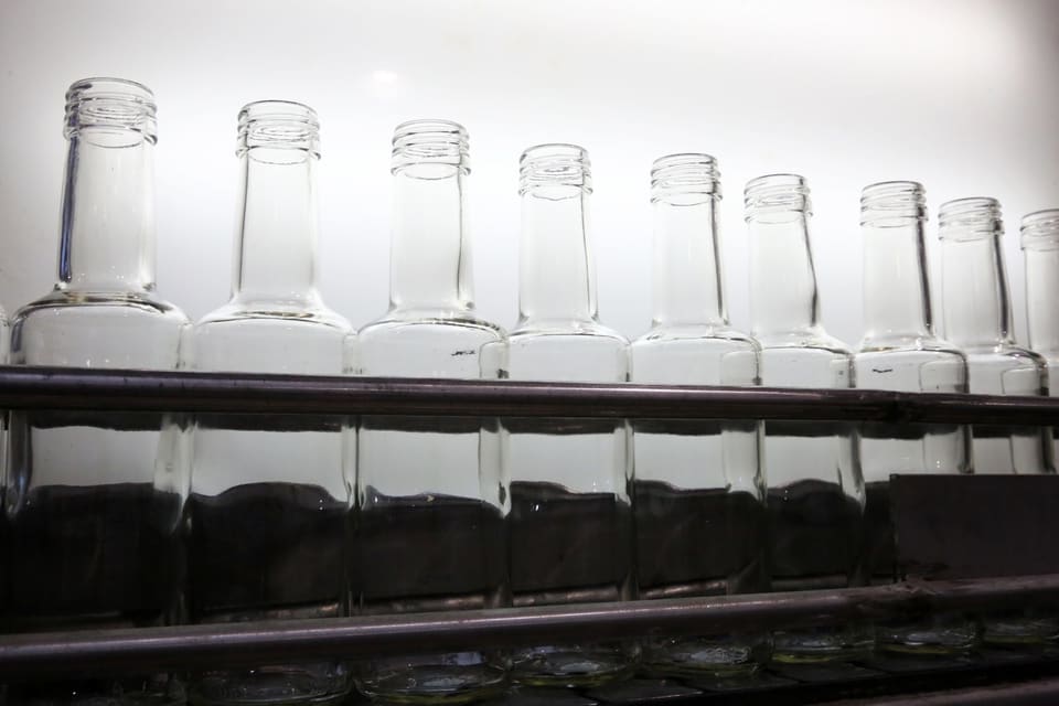 Άδειες γυάλινες φιάλες μπροστά από φωτεινή οθόνη